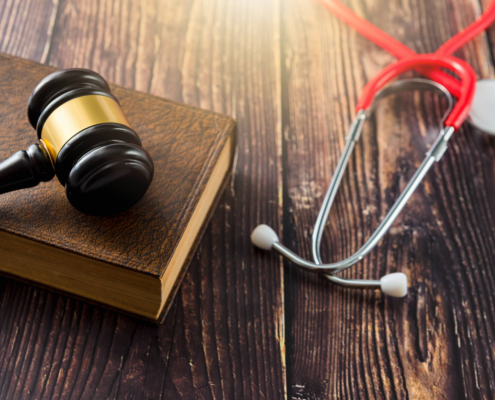 Stethoskop und Rechtshammer auf Holzuntergrund